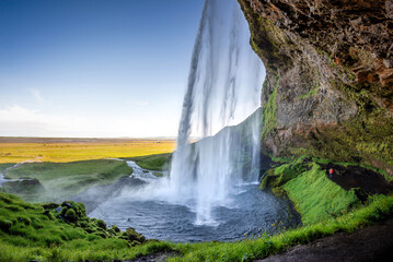 Obraz premium Walking behind Seljalandsfoss waterfall in summer, Iceland