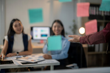 Obraz premium Two women are sitting at a desk with a man standing behind them