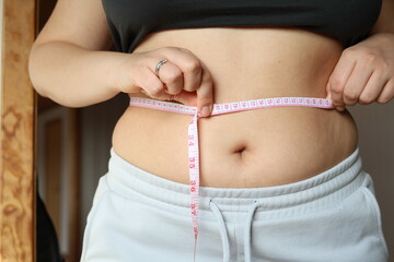 young woman measuring her waist