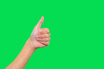 Hand giving thumbs up gesture against bright green background expressing approval and positivity in...