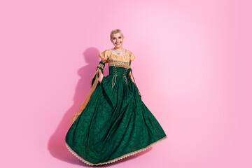 Fototapeta premium Elegant Woman in Green Medieval Dress Posing Against Pink Background