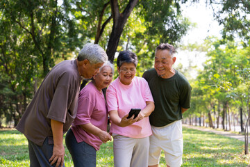 Fototapeta premium Group of happy Senior Retirement Using Smartphone and laughing outdoors at the park after a workout and spending time together, concepts about the elderly, seniority, and wellness aging