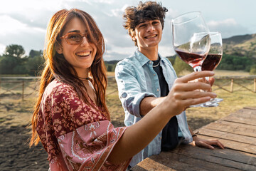 A carefree duo raising wine glasses under the sun, celebrating leisure and friendship in a scenic rural setting.