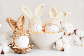 Easter eggs in crochet knitted hats with rabbit ears in nest. Easter celebration concept