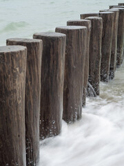 Wave breakers on the beach of Burgh-Haamstede in the Netherlands. Sea floating around the wooden poles.
