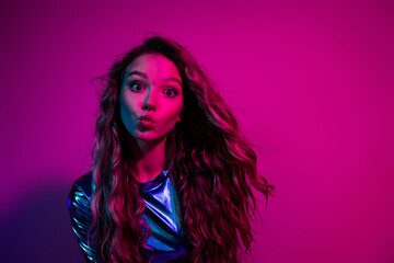 Stylish woman with blonde hair poses against a vibrant pink background, embodying glamour and joy on a festive night out.