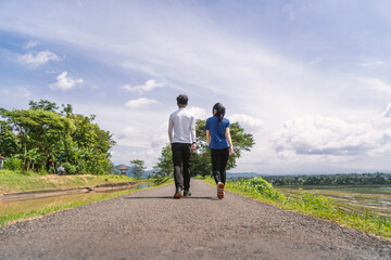 Obraz premium back view of active asian couple walking exercise at rural area