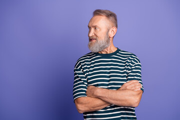 Portrait of a mature man with a beard in a striped t-shirt on a violet background, looking to the side confidently