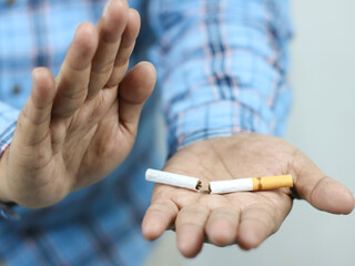 Stop smoking, quit smoking or no smoking cigarettes. Man holding broken cigarette in hand concept
