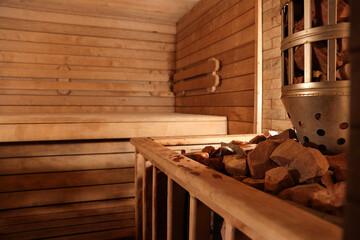Wooden sauna with bench, stove and hot stones