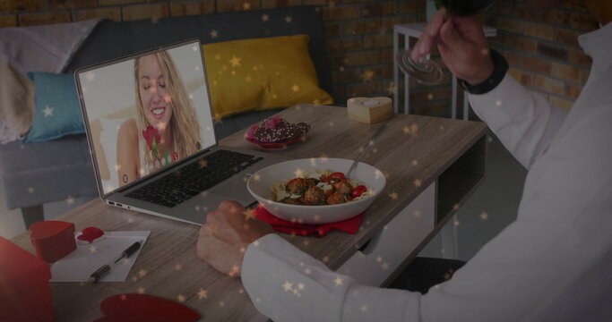 Image of hearts falling over caucasian man eating pasta having image call with caucasian woman