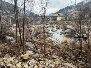Panoramic view of a river after heavy rains and flooding, in a rocky landscape, with a bridge and a small village in the background, Pied-de-Borne, Cévennes, Lozère, France
