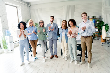Group of professional colleagues standing together in modern office, showcasing teamwork and...