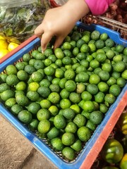 Customer Selects Fresh Green Limes at a Local Market Stall