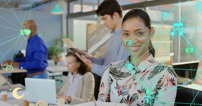 Image of network of connections with icons over diverse colleagues working in office