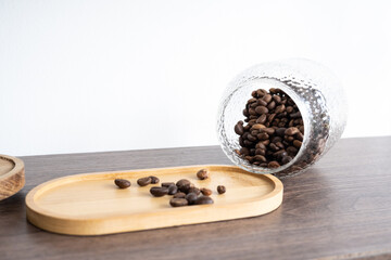 Roasted coffee beans in a glass jar collapsed on a wooden stand. on a board