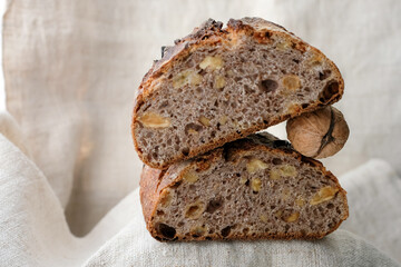 Walnut raisin sourdough bread on a hemp tablecloth. Pyramid of bread and walnut. Copy space. Shallow depth of field.