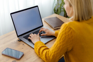 Woman working on laptop at home office during daytime