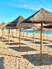 Beach Umbrellas On Sandy Tropical Beach With Blue Waves And Blue Cloudy Sky In Light And Shadows