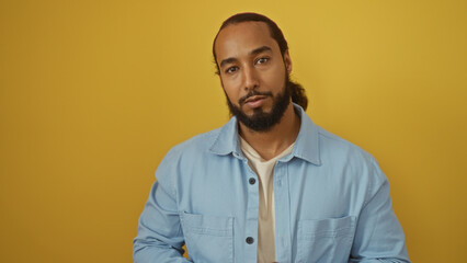 Young arab man with beard wearing light blue shirt against isolated yellow background portrays...