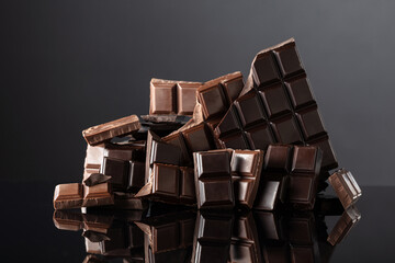 Broken bitter and milk chocolate bars on a black background.