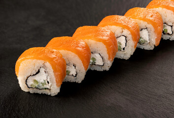 Delicious salmon sushi roll with cream cheese on slate surface