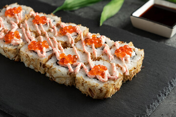 Delicious sushi roll with red caviar and creamy sauce garnish on slate plate