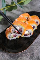 Delicious salmon sushi rolls with cream cheese on black plate