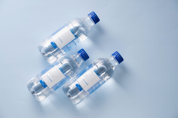 Three bottles of fresh mineral water on light blue background