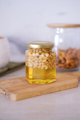 Cedar nuts with honey in glass jars on white wooden boards.