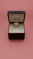 Elegant gold ring in black velvet box on champagne background
