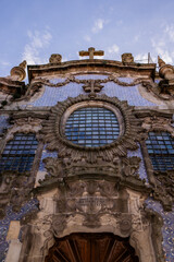 A stunning low-angle shot of a historic baroque-style church facade, adorned with traditional Portuguese azulejo tiles in blue and white