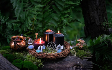 witch cauldron, burn black candles, amulet and crystals in forest, dark natural background. occult...