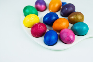 Colorful dyed easter eggs arranged on a white plate. multicolored eggs in bright hues of yellow, purple, green, and blue. Color contrast, creativity, holiday decoration. Copy space. Selective focus