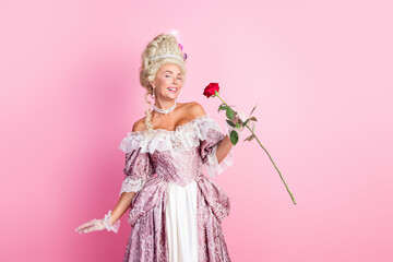 Elegant woman in historical costume holding a rose on a pink background, embodying royalty and...