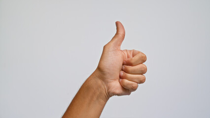 Man's hand showing thumbs up gesture against a plain background conveying approval and positivity
