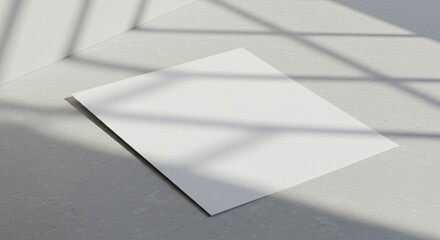 A blank white sheet of paper lies on a textured light gray surface, illuminated by soft natural light, with shadows from a window frame creating an artistic and minimalist composition.