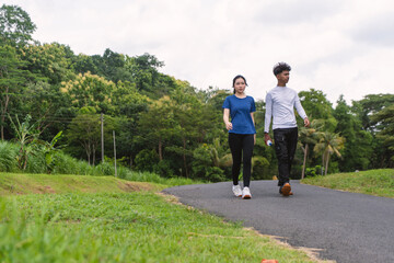 Obraz premium active young asian couple holding water bottle while walking exercise at rural area