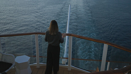 Woman enjoying view on cruise ship deck overlooking water and horizon, capturing serene moment at...