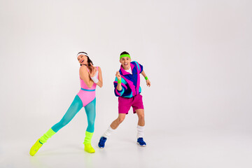 Energetic young couple in vibrant 80s fitness outfits having fun in a dance workout.