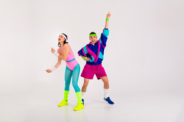 Energetic couple enjoys retro fun in colorful fitness attire on a white background, perfect for...