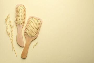 Wooden hair brushes and spikes on beige background, flat lay. Space for text