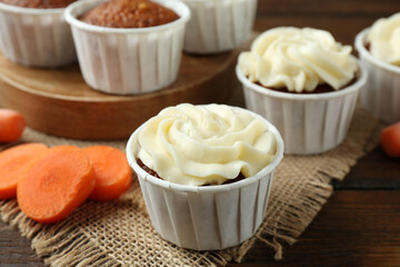 Tasty carrot muffins and fresh vegetable on wooden table, closeup