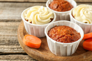 Delicious carrot muffins and fresh vegetable on wooden table, closeup