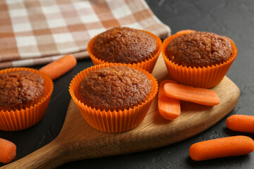 Delicious carrot muffins with fresh vegetables on black table, closeup