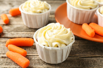 Delicious carrot muffins and fresh vegetables on wooden table, closeup