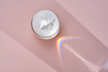 An open jar of cream with its texture on a pink background.
