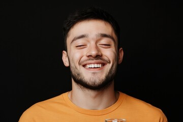 Fototapeta premium Smiling young man radiates joy, dressed in bright orange on dark