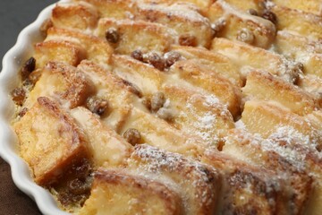 Delicious bread pudding with raisins and powdered sugar in dish, closeup