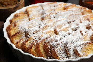 Delicious bread pudding with raisins and powdered sugar in dish, closeup